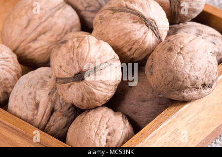 Macro view of a group of walnuts in a brown wooden box with a shallow depth of field Stock Photo
