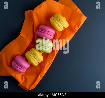 multicolored macarons on an orange napkin, empty space on the right, top view Stock Photo