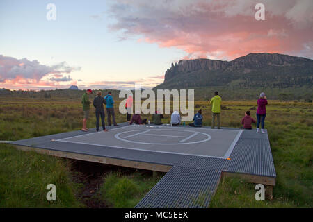 Hikers on the helipad at New Pelion Hut, midway along the Overland Track, looking to Mt Oakleigh Stock Photo