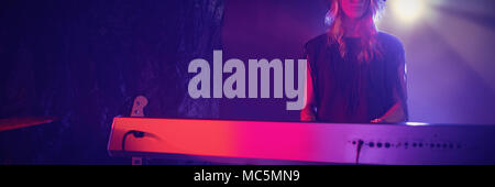 Beautiful female performer playing piano in nightclub Stock Photo