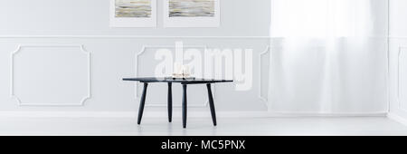 Black table with five candles standing in the middle of a white interior with window Stock Photo
