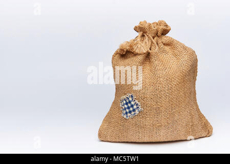 A filled bag of burlap with a patch on a white background. Stock Photo
