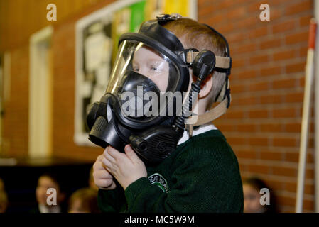A young student from Great Heath Academy tries on firefighter gear from the 100th Civil Engineer Squadron Fire Department during a school visit in Mildenhall, England, March 27, 2018. The firefighters showed the children what their gear is used for, explained how it protects them and allowed the children to try on the gear. Stock Photo