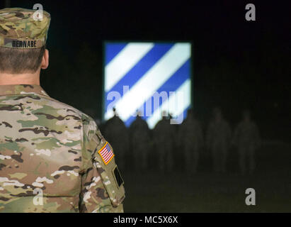 Task Force Marne Commander Brig. Gen. Sean Bernabe, stands at the position of attention as he watches approximately 60 Soldiers march towards him under the cover of darkness at Fort Stewart, Georgia. The first group of 3rd Infantry Division Soldiers returned home from a nine month deployment to Afghanistan April 1, 2018. Stock Photo