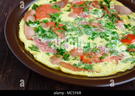 Omelet with sausage and fresh tomatoes and herbs on a clay plate and quail eggs. The top view. Breakfast Stock Photo