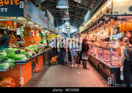 A view inside La Boqueria indoor public market in Barcelona, Spain. one one side of the aisle is a delicatessen and on the other a greengrocers. Stock Photo