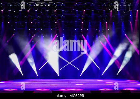 Illuminated empty concert stage with haze and rays of red, purple and blue light. Background for music show Stock Photo