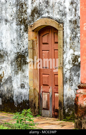 Old and aged historic wooden church door in the city of Ouro Preto, Minas Gerais with a stone frame Stock Photo