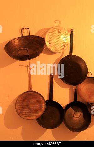 Pots and pans hanging on a yellow wall Stock Photo