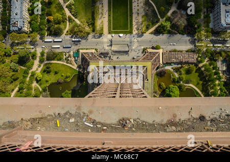 Eiffel Tower from the top viewing down to the streets and Champ de Mars gardens below. Paris, France. Tiny tourists below. Coaches Stock Photo