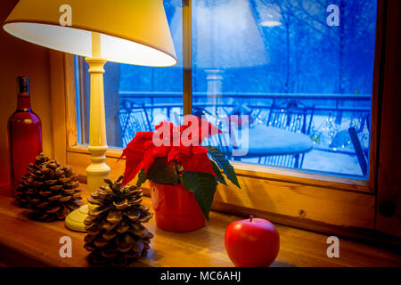 Warm lamp and xmas decorations on a windowsill, with winter landscape seen through the window. Stock Photo