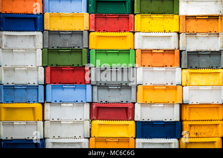 Stacked returnable boxes of fish in various colors. Stock Photo
