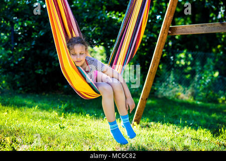 Child girl sleeping in a sunny hammock on vacation. Stock Photo