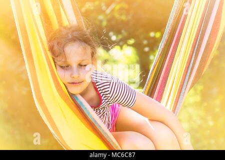 Child girl sleeping in a sunny hammock on vacation. Stock Photo