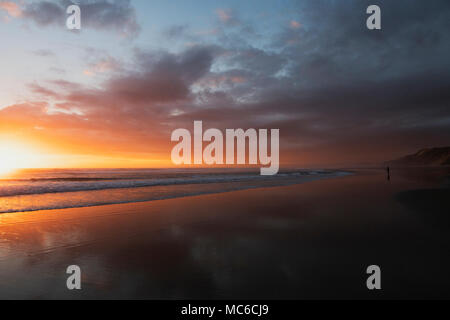 Fisherman at sunset on a Northalnd beach in New Zealand Stock Photo
