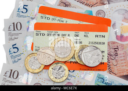 Two British train tickets for Standard off-peak travel out and return rail fares with new five and ten pound notes and pound coins. England UK Britain Stock Photo