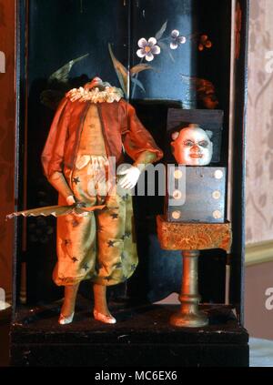 Magical atuomaton by Jean-Marie Phalibois. c. 1875. The magician raises his fan to his face and lowers it, to reveal that his head has disappeared. It emerges from the dice box to the magician's left. From the Museum of Automata, York Stock Photo