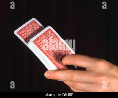 Stage Magic - Card Tricks The deck of cards has a special area cut out at the bottom. Only the selected card is uncut. This device enables the magician to push the card upwards, either with his finger or with a hidden string. Stock Photo