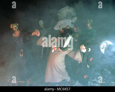 Black Magic Group of people in a black magic/witchcraft burlesque, dressed in outlandish costumes and masks, dancing within a magical circle Stock Photo