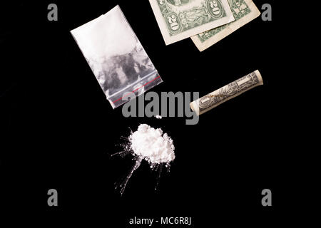 cocaine, Herion or other illegal drugs that are sniffed by means of a tube or injected with a syringe and money, isolated on black glossy background Stock Photo