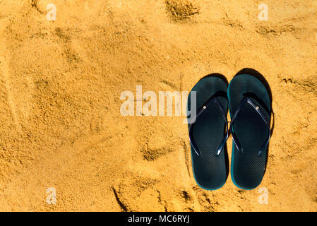 Summer slippers. Navy blue flip flop on yellow sand beach background ...