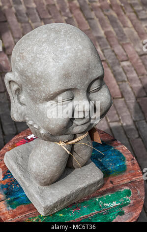 a laughing Buddha head of stone placed on a round hopping table Stock Photo