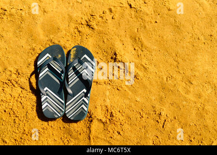 Summer slippers. Navy blue flip flop on yellow sand beach background ...