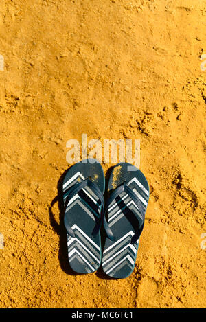 Summer slippers. Navy blue flip flop on yellow sand beach background ...