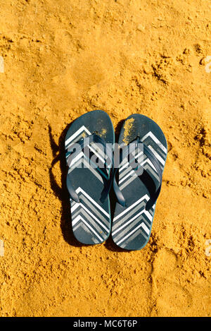 Summer slippers. Navy blue flip flop on yellow sand beach background ...