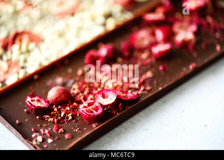 Handmade chocolate bars with dried cranberries, raspberries and pistachios, strawberries, nuts. Dark and milk chocolate mix, assortment. Top view. Stock Photo