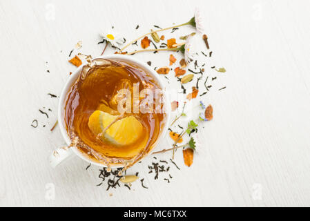 cup of tea on white table with lemon slice splashing Stock Photo