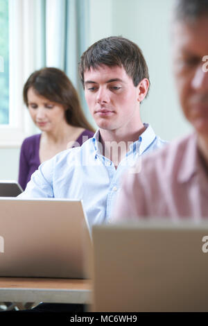 Young Man Working On Laptop In Adult Education Class Stock Photo