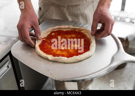Fresh original Italian raw pizza, preparation in traditional style. Hands of chef baker making pizza at kitchen Stock Photo
