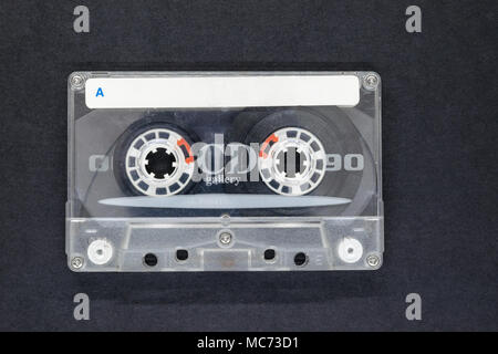 Old, dusty, scratched audio cassette on black background surface with free space. Free white space on music cassette with letter A. On cassette writte Stock Photo
