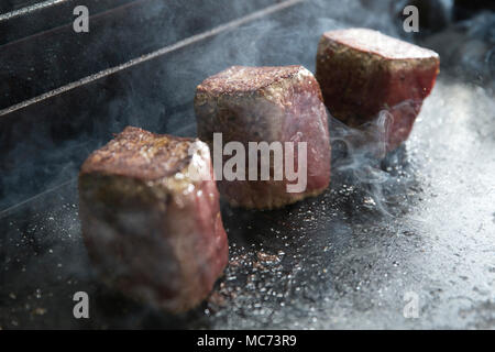 three pieces of beef fillet cooking on a hot-plate Stock Photo