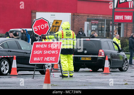 A road worker holding a stop sign to halt traffic during roadworks in Liverpool, Merseyside Stock Photo