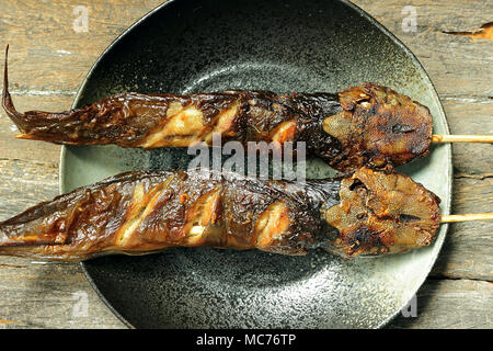 Two grilled catfish on a plate. And put on wooden background. Stock Photo