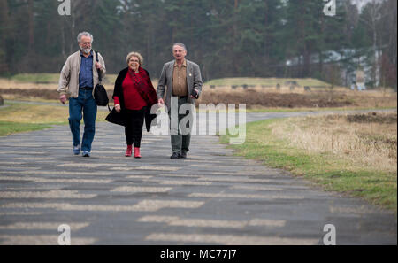 13 April 2018, Germany, Lohheide: Julius Maslovat (L-R), Lous Steenhuis-Hoepelman and Ivan Lefkovitz, who were child inmates in Bergen-Belsen, walking over the site of the former concentration camp. The doll was the only thing she had with her in the camp. From the approximaately 120 000 detained people at the concentration camp in the Lueneberg Heath, from all parts of Europe, there were also around 3500 children under 15 years of age. Photo: Philipp Schulze/dpa Stock Photo