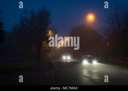 Vehicles travelling along a suburban road at night in England. Stock Photo