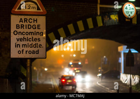 Traffic passing beneath a railway bridge at night in a town in the UK. Stock Photo