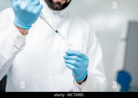Man putting sample into the test tube at the laboratory, close-up view Stock Photo