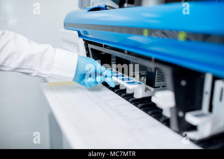 Close-up view on the hand putting samples into the medical analyzer Stock Photo