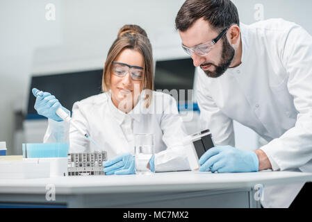 Laboratory assistants in uniform and protective glasses working with test tubes in the medical laboratory Stock Photo