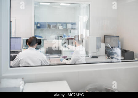 View through the glass on the laboratory with medic doing analysis Stock Photo