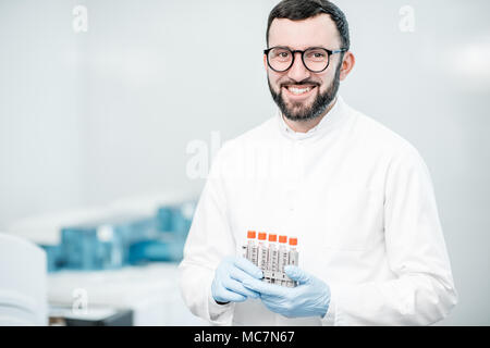 Portrait of a male technician standing with test tubes in the laboratory Stock Photo