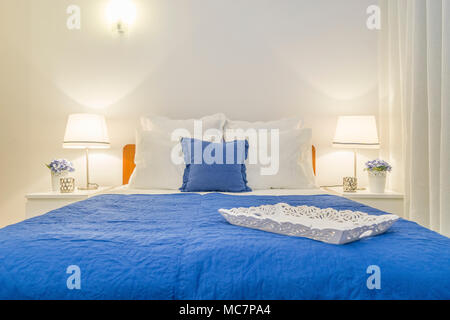 Carved wooden tray decorating elegant bedroom with white and blue cushions Stock Photo