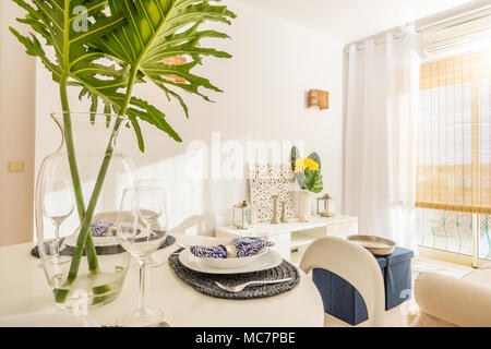 Living room with a dining table in modern, luxury apartment illuminated by afternoon sun Stock Photo