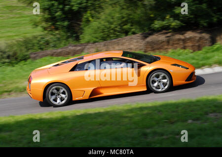 Profile (side view) of an orange Lamborghini Murcielago driving fast