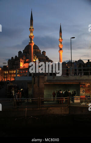 People standing on the Galata Bridge with the New Mosque in the background - Istanbul, Turkey Stock Photo