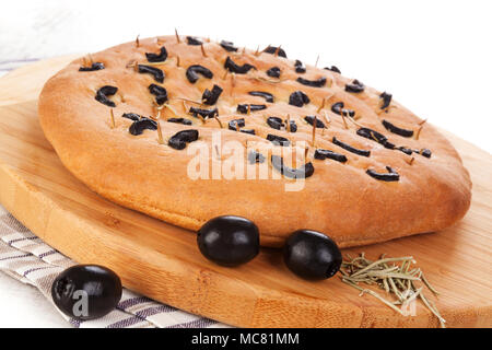 Italian foccacia bread with black olives on wooden choping board. Stock Photo